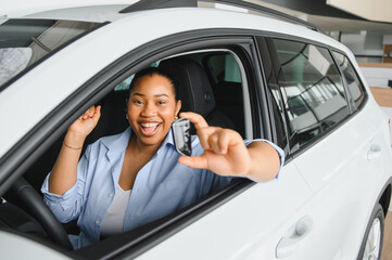 Excited woman showing new car key while sitting in vehicle