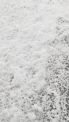 Discover the mesmerizing beauty of sea foam swirling over wet sand forming intricate and transient patterns