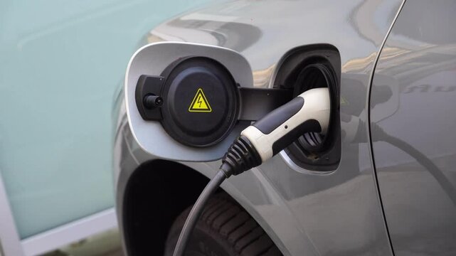 Electrical car recharging Modern electric car charging at the charger station, Electrical nozzle is inserted into an electrocar