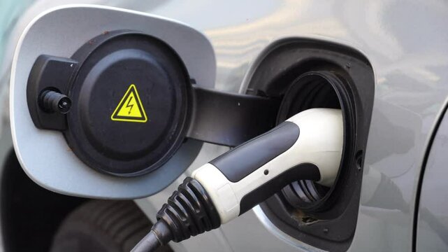 Electrical car recharging Modern electric car charging at the charger station, Electrical nozzle is inserted into an electrocar