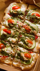 Roman square pizza on thick dough with mozzarella, tomatoes, chicken, zucchini and pesto sauce
