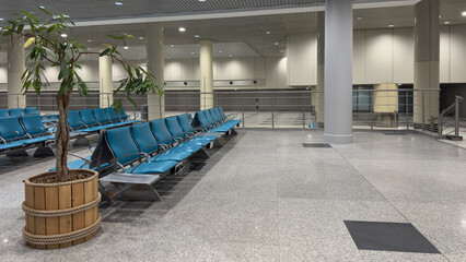 Spacious airport waiting area with empty chairs.