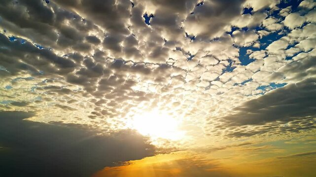 Sun rays beaming through a dense blanket of altocumulus clouds during golden hour with blue sky peeking through