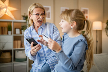 grandma and granddaughter have online shopping in the living room