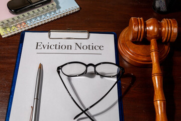 An eviction notice document lies beside a gavel on a wooden desk, representing legal proceedings,...