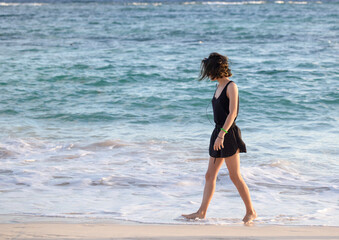 pretty young woman is walking by the sea