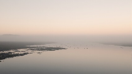 Obraz premium Tranquil inlet at sunrise with misty waters and distant silhouettes of wading birds Serene nature scene for relaxation
