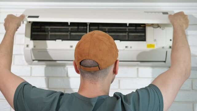 Happy man repairing conditioner. A view of happy man with good mood repair the air conditioner in the house.