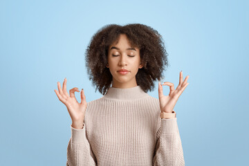 Calm woman relaxing, meditation, stress-free relief at work concept. Peaceful young african american lady, practicing yoga, breathing exercises with closed eyes, isolated on yellow background