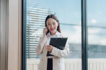 Fototapeta premium Smiling Asian Businesswoman on Phone with Clipboard