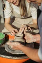 Potter teaching student how to create clay vase on pottery wheel