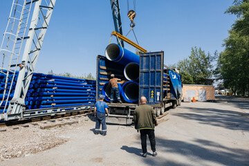 Loading cast iron pipe into truck for transportation by overhead crane