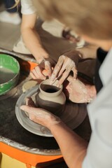 Potter creating clay vessel with apprentice on pottery wheel