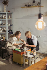 Senior woman learning pottery making with teacher