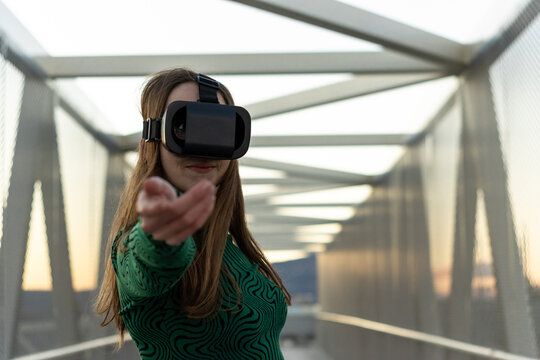 Woman wearing vr headset interacting with virtual reality metaverse on modern bridge