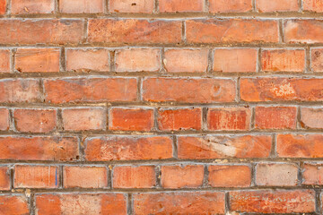 Red brick wall showing signs of age and weathering, with a random pattern, creates a textured and rustic backdrop, giving a sense of history,