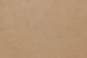 Old rough beige ochre colored cracked painted plaster wall texture. Earth coloured grunge texture, building facade. Closeup of historical house detail. Faded neutral backdrop, empty copy space.