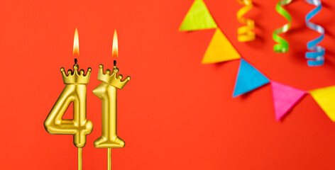Number 41 candle - Birthday celebration on an orange background with pennants