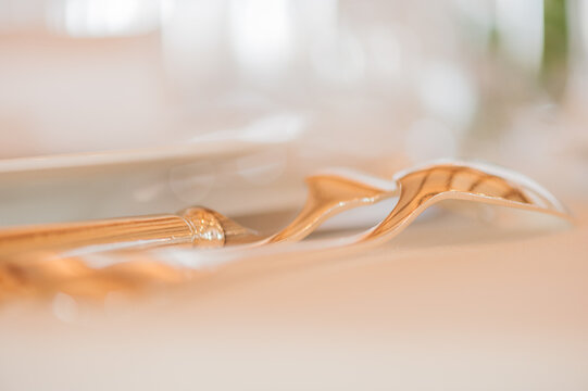 Close-up of an elegant  place setting on a table with Gold cutlery