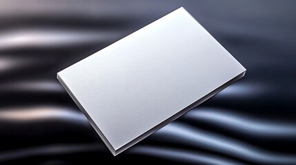 A pristine blank business card lying on a smooth, reflective surface with soft lighting