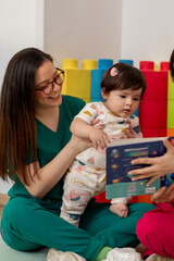 Pediatrician reading a book to baby girl in colorful office