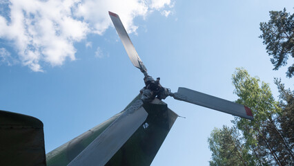 A close-up view of a vintage Soviet helicopter rotor, set against a bright blue sky, highlighting...