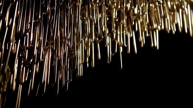 Abstract arrangement of shiny golden staples hanging down against a dark background, creating a textured metallic pattern.