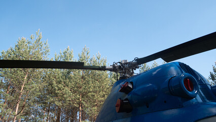 Rotor blades of a vintage Soviet helicopter overlook a lush green forest, highlighting the design and mechanics used in aviation during the USSR era.