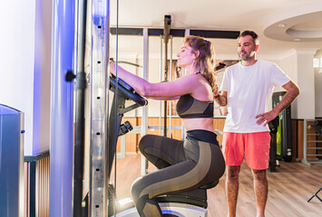 Couple working out in home gym, Personal trainer assisting client