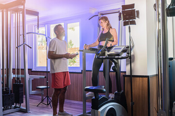 Couple working out in home gym, Personal trainer assisting client