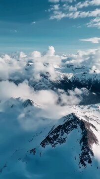 Aerial View of Snow-Covered Mountain Peaks Piercing Through Clouds