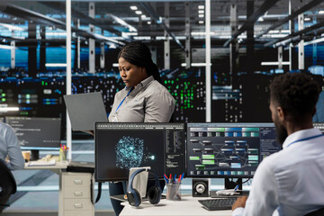 Fototapeta premium Data center manager supervising engineers implementing AI virtualization to improve resource allocation. Server hub supervisor overseeing employees doing artificial intelligence predictive analysis
