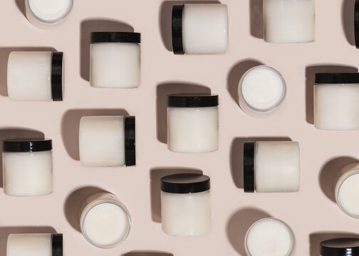 Repeating pattern of jars of beef tallow / shea butter jars on tan background 