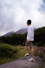 Fototapeta premium Man Exploring Nature with a Stick in a Lush Green Landscape