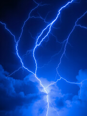 Fototapeta premium Vibrant electric blue lightning bolts crackle across a dark, stormy sky, creating a dramatic and powerful visual effect. The jagged lines illuminate the surrounding clouds with intense energy