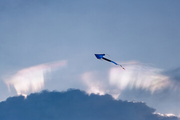 Blue and Black Kite Flying Above the Rainbow Clouds