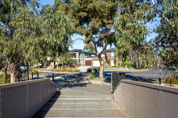 A pedestrian bridge toward a suburban residential street in Australia, lined with eucalyptus trees...