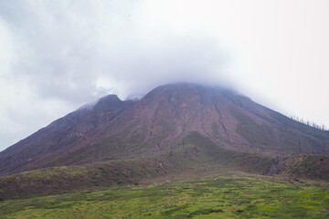 mountain landscape with green foothills and mist at the summit