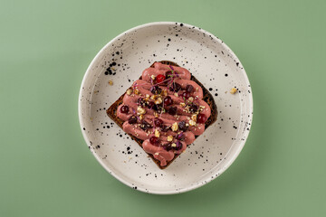 A beautifully arranged gourmet toast showcases a blend of vibrant ingredients, including creamy spreads, fresh fruits, and a sprinkle of crunch, all set against a calming green backdrop
