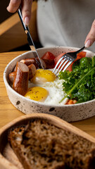 Delight in a gourmet dish with perfectly cooked eggs, succulent sausages, and vibrant greens. The warmth of the wooden table enhances the inviting atmosphere of this culinary experience