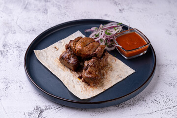 Delicate pieces of meat, expertly cooked to perfection, rest on a warm flatbread accompanied by a vibrant sauce and fresh onions. This culinary presentation invites exploration of local flavors