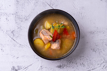 A delightful bowl filled with a vibrant fish soup, featuring tender pieces of fish, potatoes, and rich herbs, artfully arranged to entice food lovers