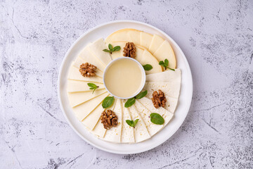 A beautifully arranged platter showcases an array of gourmet cheeses alongside walnuts and fresh mint leaves. This delectable presentation invites culinary exploration and enjoyment