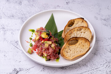 Delightful gastronomic offerings feature a finely prepared dish with fresh ingredients, combined artfully on a plate, accompanied by crispy toast. An exquisite culinary experience awaits