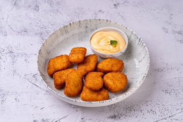 A delectable array of golden fried nuggets served in an elegant bowl alongside a smooth, creamy dipping sauce