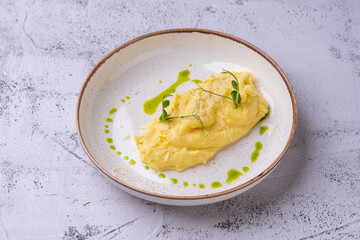A beautifully plated dish showcases a creamy omelet adorned with delicate herbs and a vibrant green drizzle