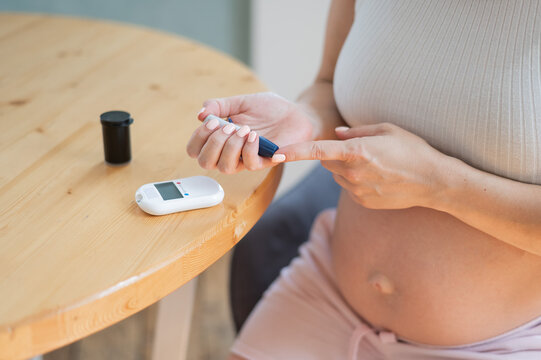 Pregnant woman doing home blood sugar test. Gestational diabetes. 
