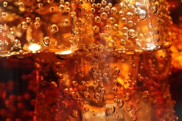 Refreshing cola with ice cubes as background, macro view