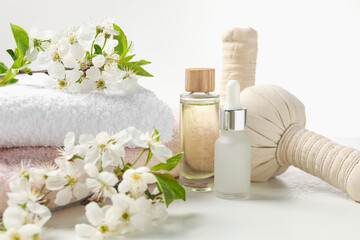 Spa products and twigs with beautiful flowers on white table, closeup