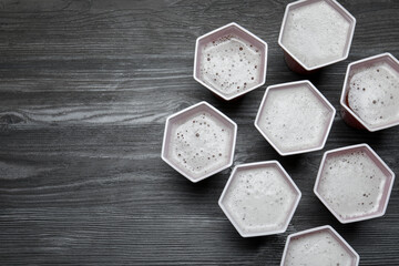 Beer pong game. Plastic cups with drinks on wooden table, flat lay. Space for text